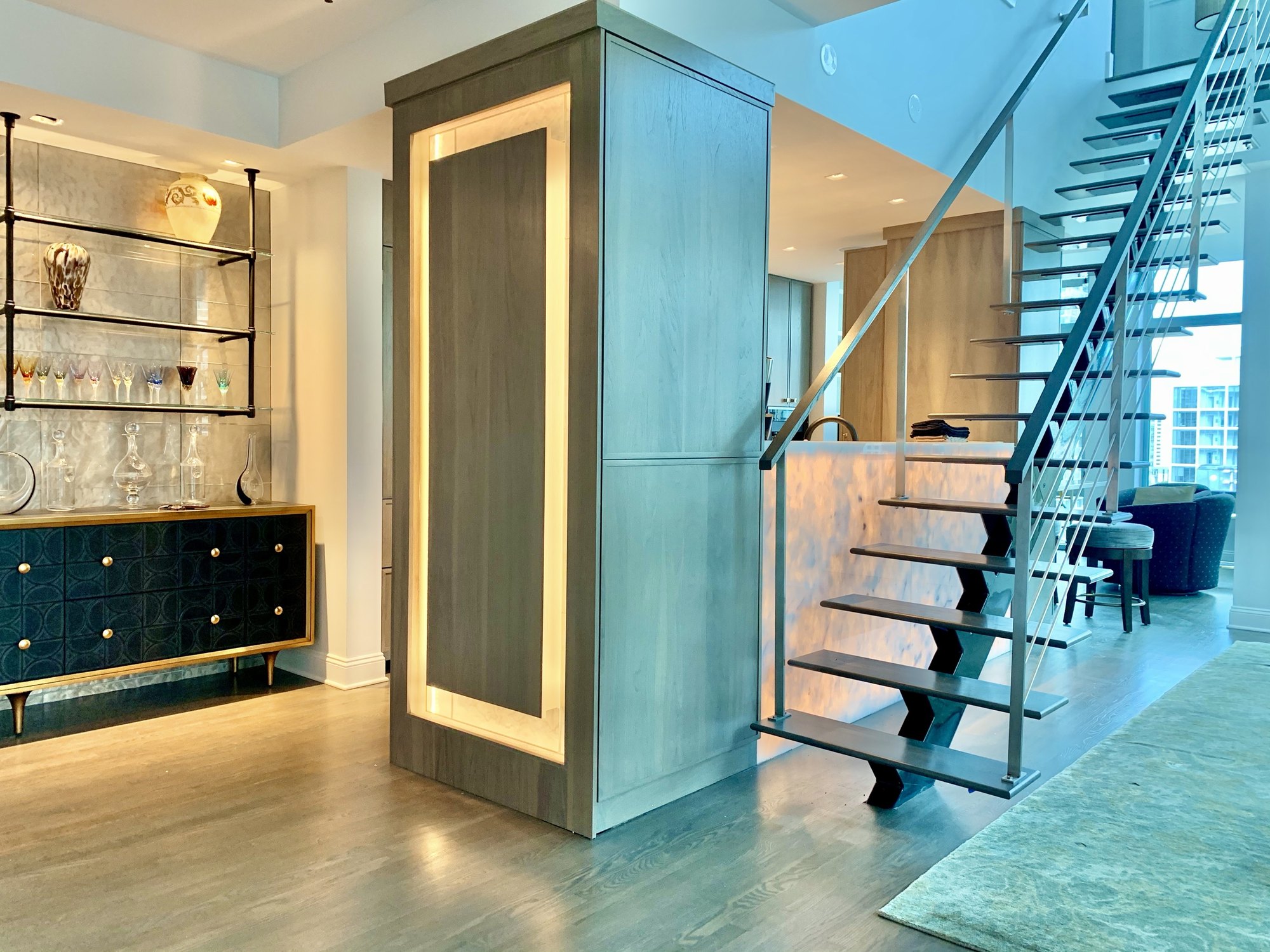Floating staircase and backlit bar in a Chicago high-rise residence by Sulika Hughes Design Build